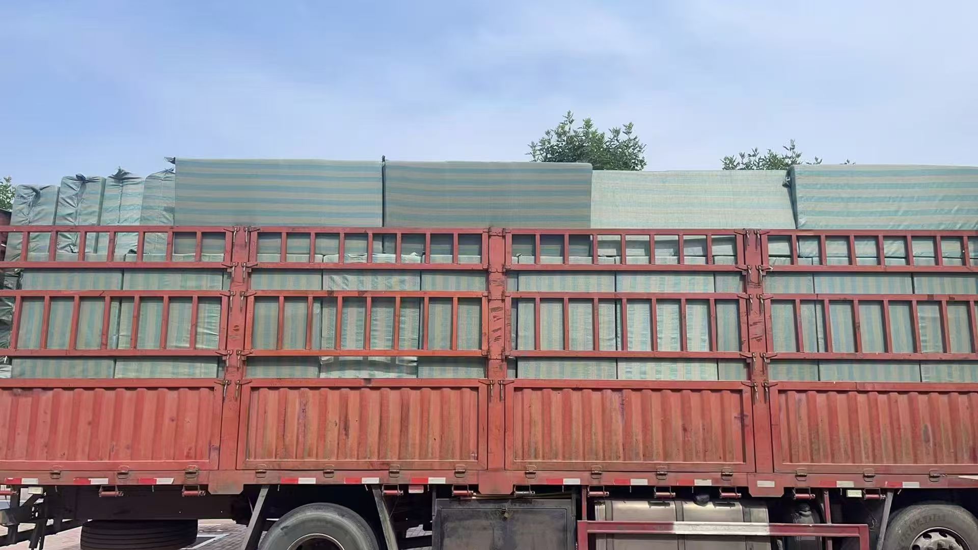 Cami&oacute;n de transporte de plataforma completa cargado con paletas de exportaci&oacute;n envueltas de ayudas a la movilidad con destino al puerto de contenedores